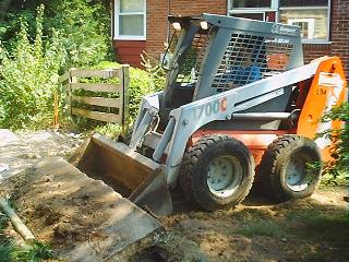 Stuart using skid steer to pull up the sidewalk