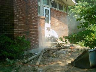 Stuart saws the stoop from the back to try to loosen it from the house