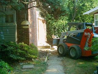 The sidewalk and Stoop with Stuart bringing in the Skid Steer